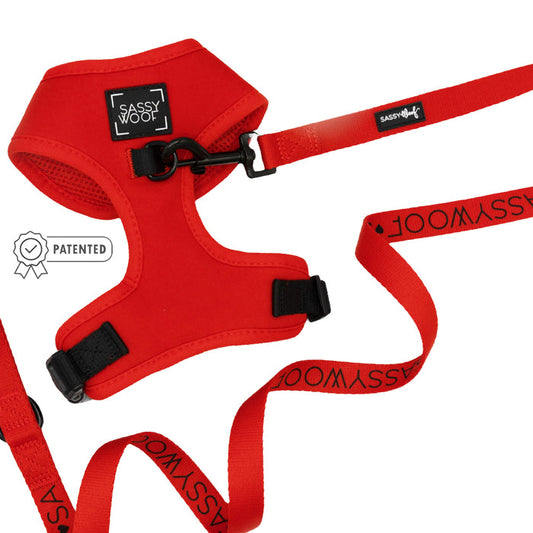 The Sassy Woof Dog Two Piece Bundle - Neon Red is shown on a white background, featuring an adjustable harness with black buckles, a Patented badge icon, and matching leash—perfect for your puppy’s growth.