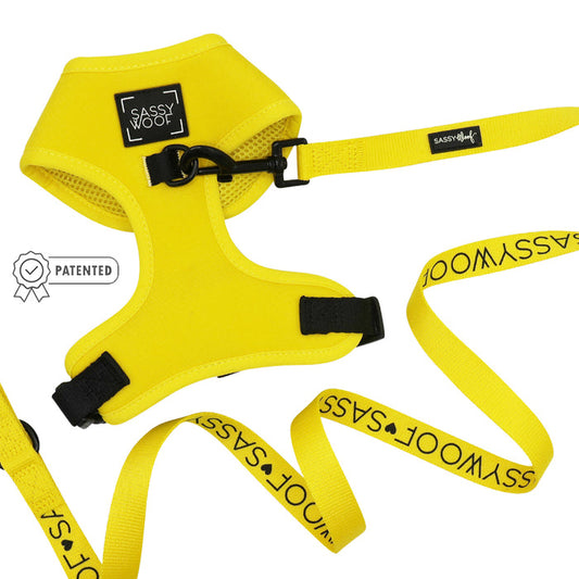 The Sassy Woof Dog Two Piece Bundle - Neon Yellow features a bright, adjustable dog harness and leash with black clasps and patented icon, ideal for your puppy's growth—shown on a white background.