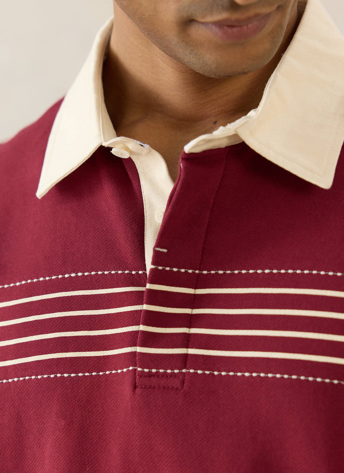 Percival Editor Striped Rugby Polo in burgundy cotton, with white stab stitching and a cream contrast collar on a model.