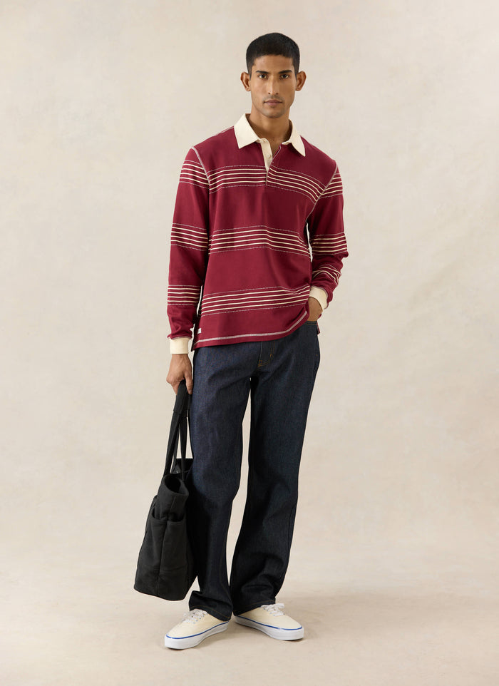 Percival Editor Striped Rugby Polo in burgundy cotton with stab stitching and cream collar, worn with jeans and a tote bag.