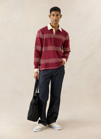 Percival Editor Striped Rugby Polo in burgundy cotton with stab stitching and cream collar, worn with jeans and a tote bag.