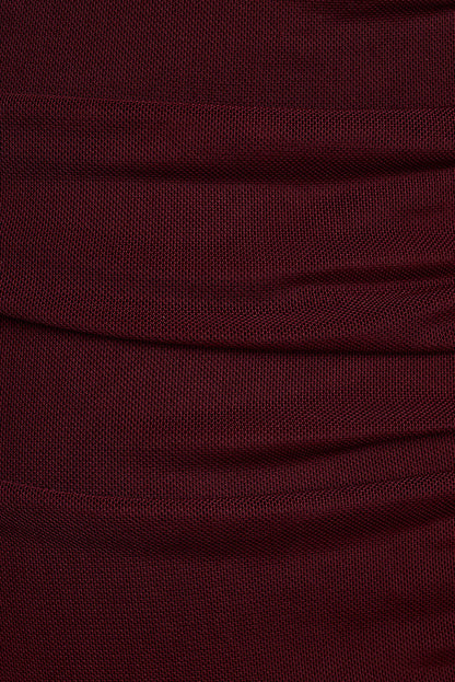 Close-up of burgundy mesh fabric with soft draped folds.