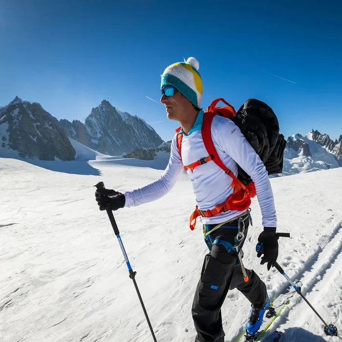 Lifestyle image of a man wearing Sub Zero Factor 2 thermal lining gloves whilst cross country skiing in the mountains surrounded by snow.