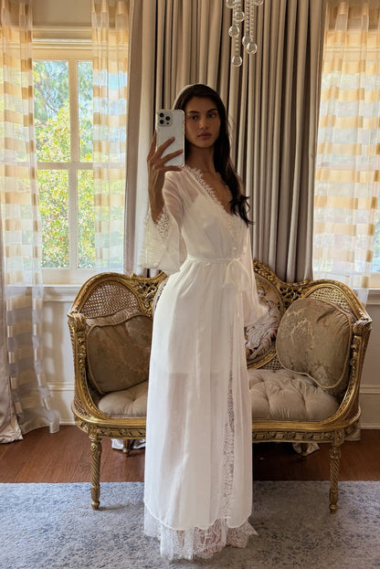 White lace-trimmed robe with bell sleeves and a tied waist sash over a satin slip dress.