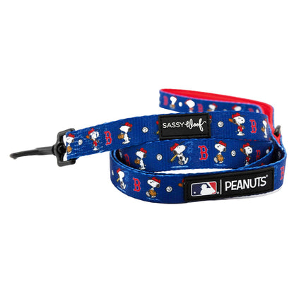 The Sassy Woof Dog Two Piece Bundle - MLB™ x Peanuts™ Boston Red Sox™ features a blue leash with Snoopy in a baseball cap, red “B”s, white dots, black hardware, and sporty Sassy Woof, MLB™, and Peanuts™ logos on black labels.