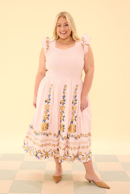 Woman wearing a pink dress with floral patterns on a checkered floor and light yellow background