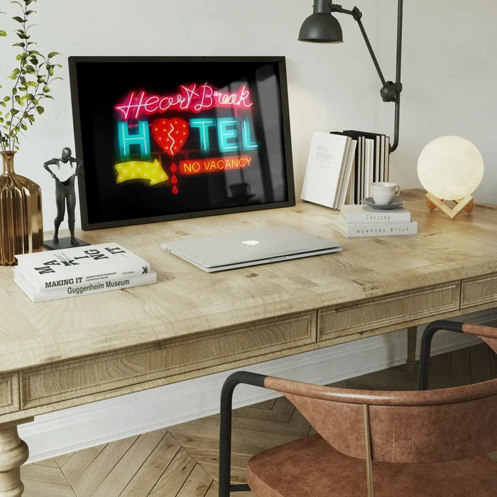 Framed Heartbreak Hotel neon sign art print with glowing red and blue text on a wooden desk with office decor.