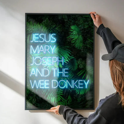 Jesus Mary Joseph Wee Donkey TV Quote Print being hung on a wall in a black frame