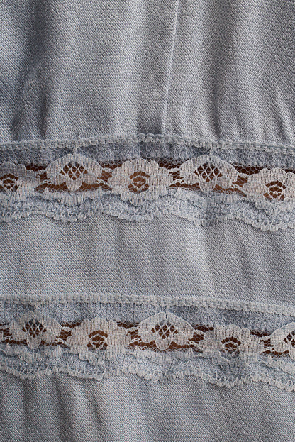 Close-up of chambray denim fabric with a scalloped lace trim insert.