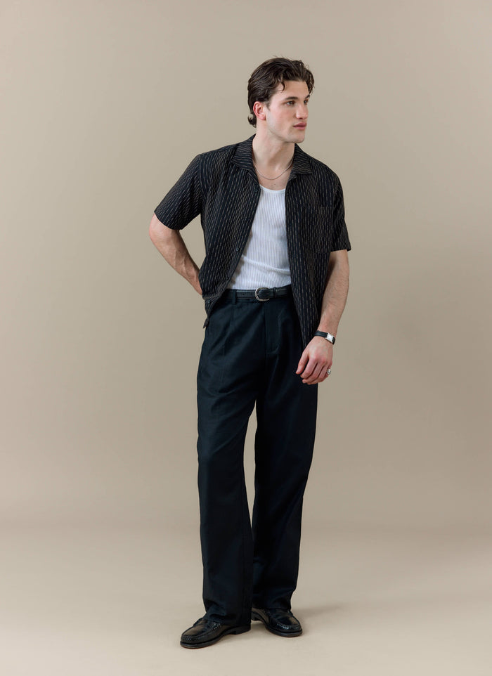 Model wearing the black Percival Leland Cuban Shirt with vertical stripe detailing and a classic Cuban collar.