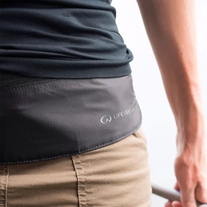 Close-up of a erson wearing a Lifeventure Waterproof Waist Wallet under a black t-shirt and cargo shorts