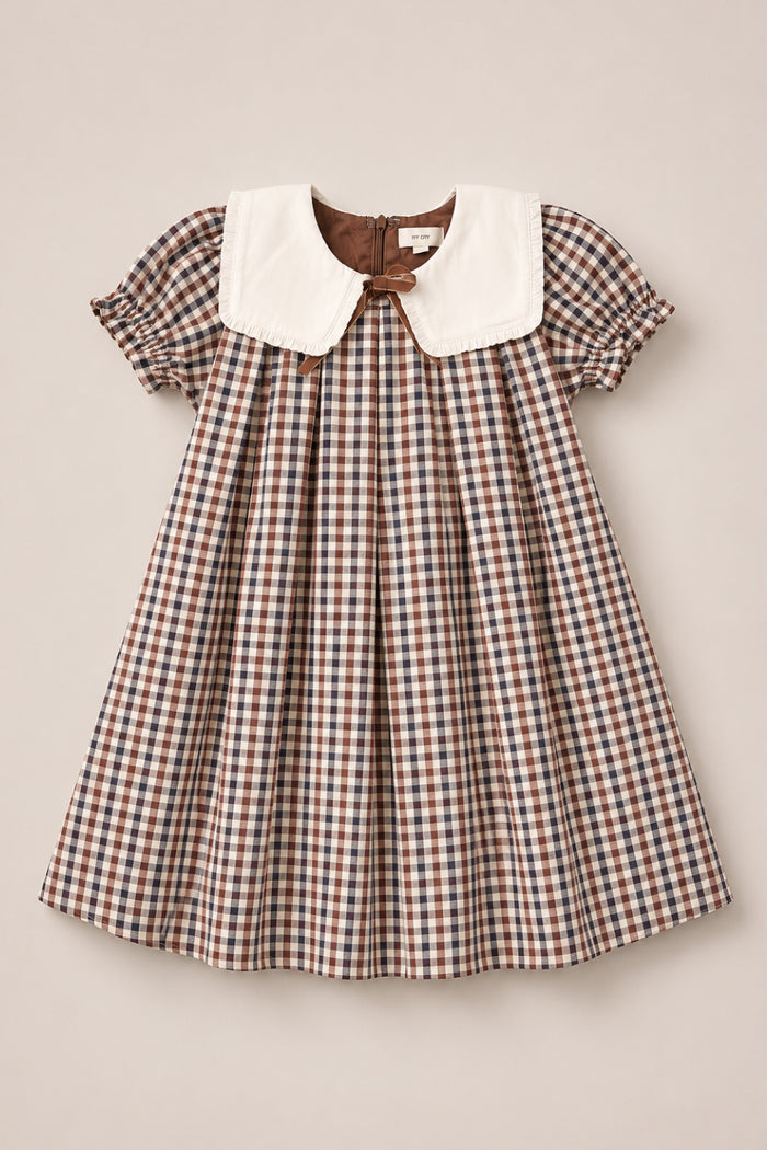 A short-sleeved Mini Emery Dress in Chestnut Gingham by Ivy City Co, featuring a large white Peter Pan collar and gathered puff sleeves, displayed flat on a light beige background—perfect as a classic girls’ cotton dress for any occasion.