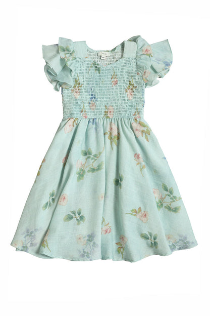 The Mini Hattie Dress in Roselyn Blue by Ivy City Co is a light blue, short-sleeved children’s dress with ruffled sleeves, a smocked bodice, pink and green floral pattern, and made from a comfortable cotton-linen blend.