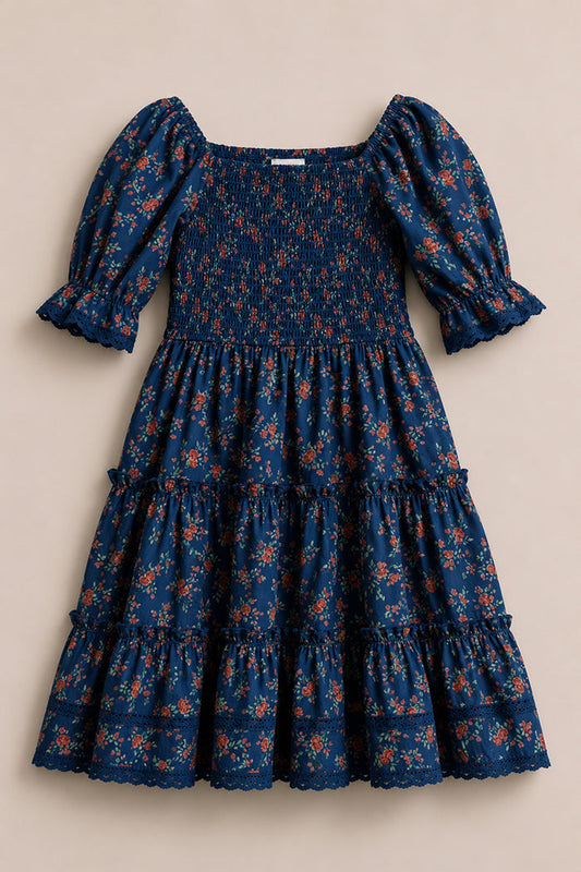 The Mini Madeline Dress in Midnight Vibrant Chintz by Ivy City Co is a blue girls' midi dress with a smocked bodice, puff sleeves with ruffled cuffs, and a tiered skirt. Features a charming red and orange floral chintz print.