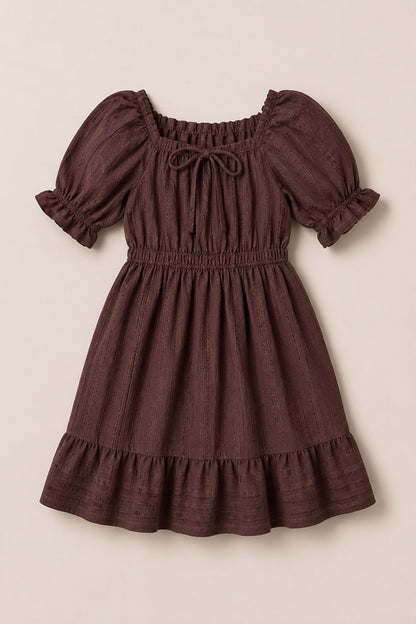 The Ivy City Co Mini Maleah Dress in Warm Cocoa is crafted from soft viscose and showcases puff sleeves, a ruffled hem, an elastic waist, and a tie at the square neckline. The dress is displayed laid flat on a light background.