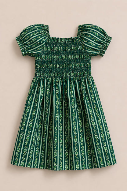 The Mini Sunday Best Dress in Pine Felicity Floral by Ivy City Co is a green girls’ cotton dress with vertical stripes, a fitted shirred bodice, puffed sleeves, and a gathered skirt featuring the signature floral pattern.