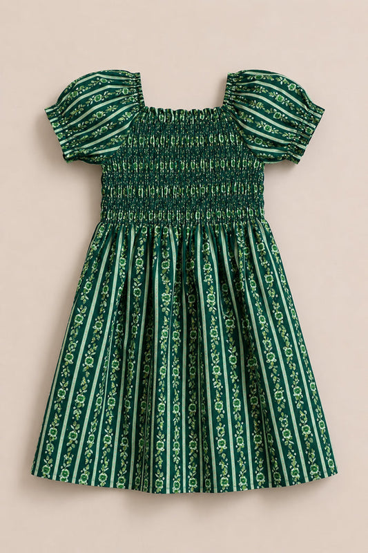 The Mini Sunday Best Dress in Pine Felicity Floral by Ivy City Co is a green girls’ cotton dress with vertical stripes, a fitted shirred bodice, puffed sleeves, and a gathered skirt featuring the signature floral pattern.