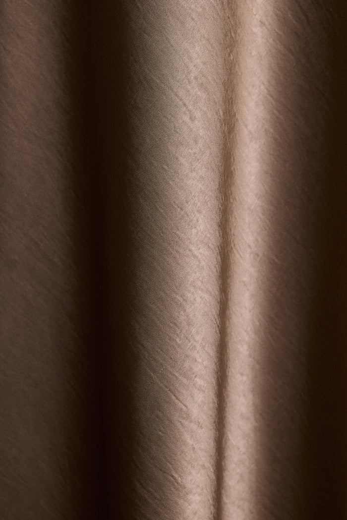 Close-up of taupe satin fabric with soft draped folds.