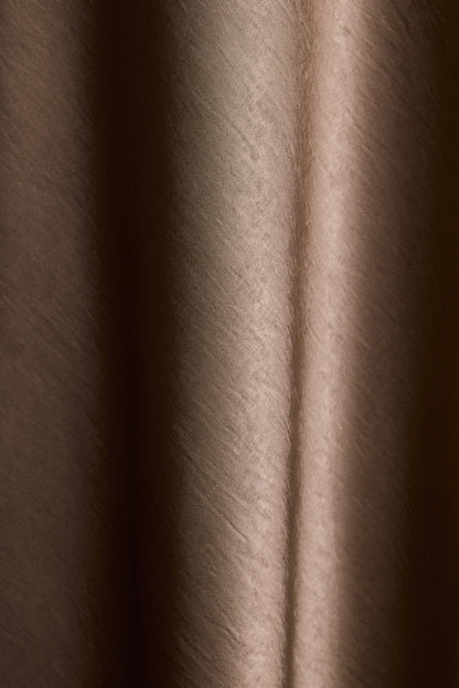 Close-up of taupe satin fabric with soft draped folds.