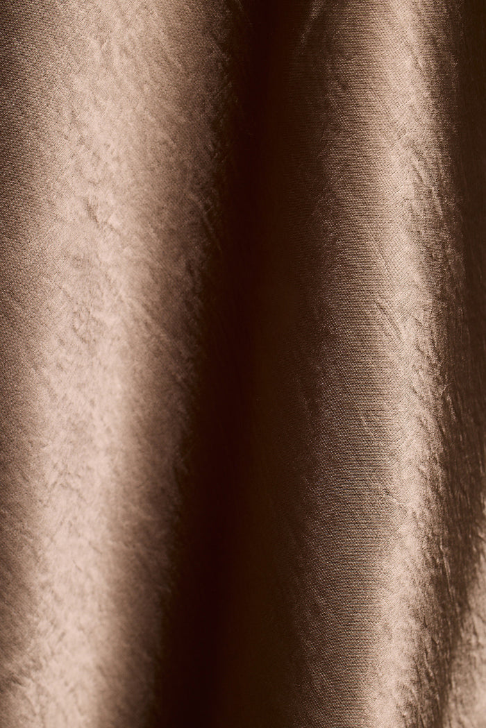 Close-up of brown satin fabric with soft draped folds.