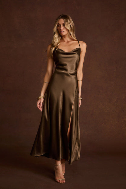 Olive satin cowl neck slip dress with thin straps, a side slit, and gold jewelry.
