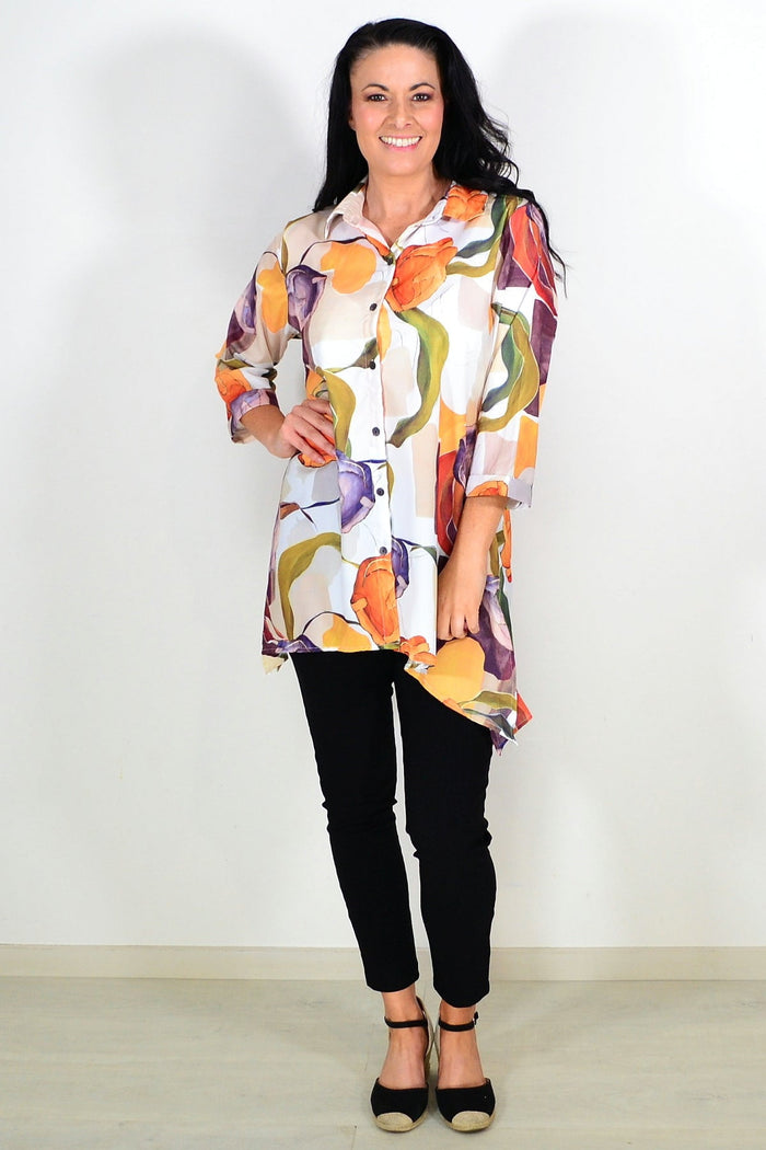 Orange artwork swirls Wishstone tunic shirt with vibrant design and flowing fabric, displayed on a hanger.