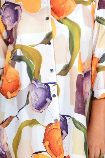 Orange artwork swirls tunic shirt by Wishstone, featuring vibrant abstract design and lightweight fabric, displayed on a hanger.