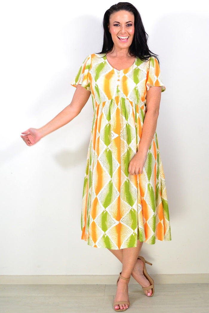 Orange and green patterned Hourglass tunic dress displayed on a mannequin, showcasing its vibrant design and flowing fabric.