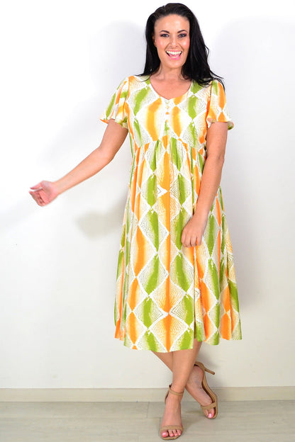 Orange and green patterned Hourglass tunic dress displayed on a mannequin, showcasing its vibrant design and flowing fabric.