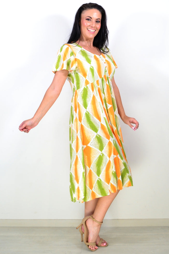 Orange and green patterned Hourglass tunic dress with a relaxed fit, displayed on a hanger against a neutral background.