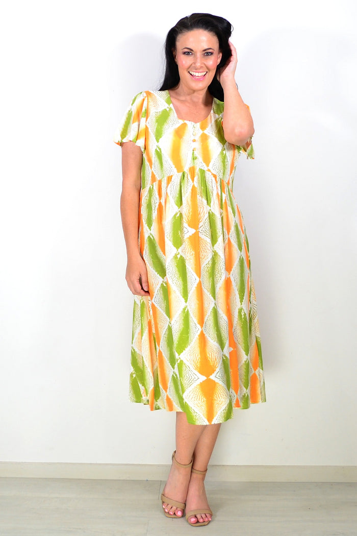 Orange and green patterned Hourglass tunic dress displayed on a hanger with a flowing fabric design.
