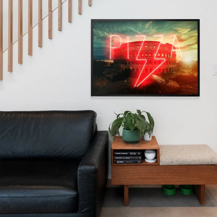 Framed neon-style pizza sign print featuring the Roman Colosseum at sunset, displayed in a modern living room interior.
