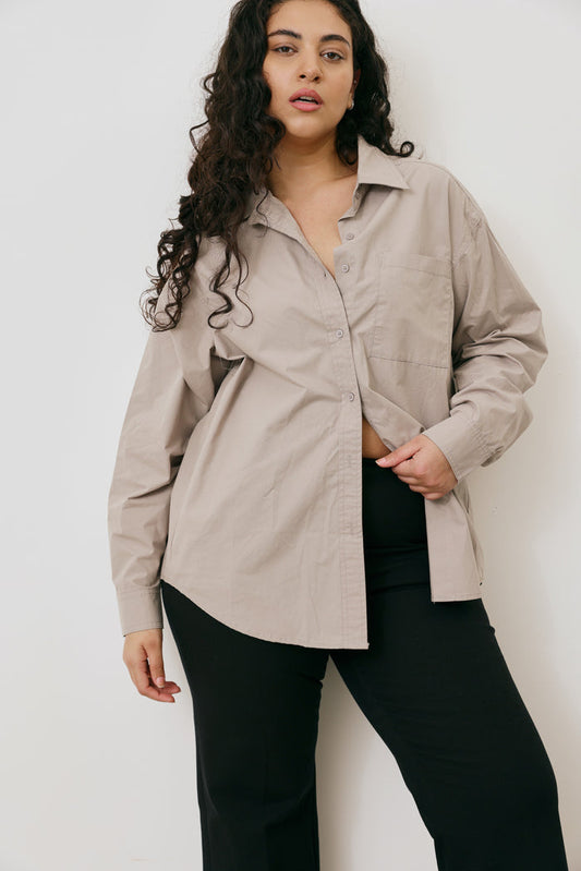 Woman wearing a beige shirt over a black top against a white background
