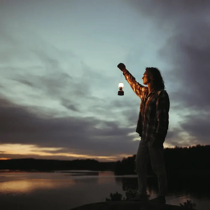 Person holding a Primus Easy Light Duo gas  lantern by a lake at dusk