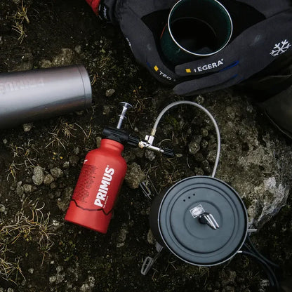 Camping stove attached via its Ergo pump to a Primus fuel bottle on rocky ground