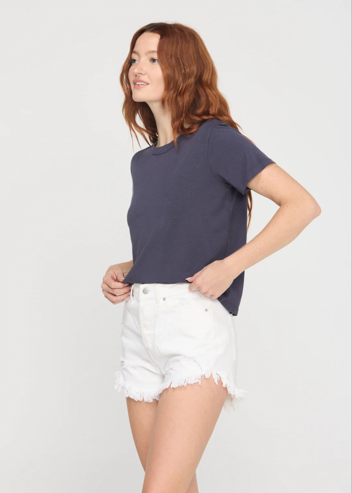 Woman wearing a charcoal grey crewneck t-shirt with white denim shorts