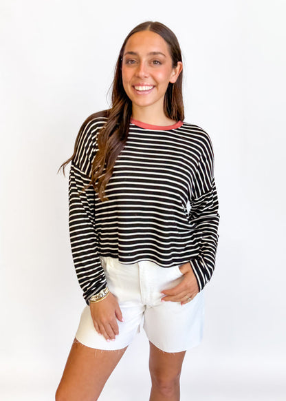 Woman wearing a black and white striped long-sleeve top and white shorts on a white background