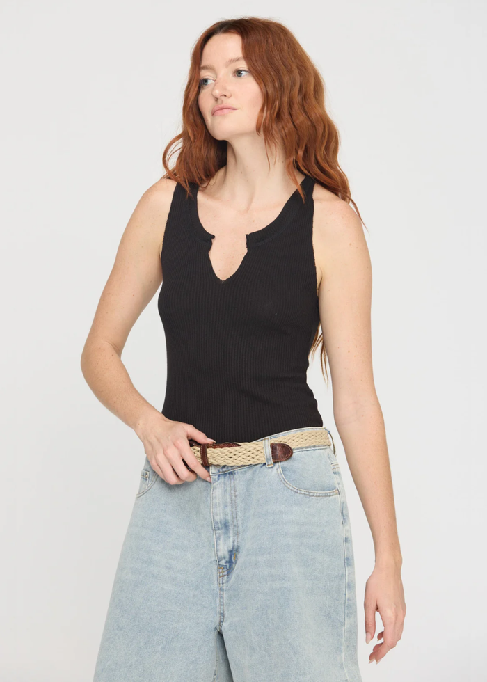 Woman wearing a notch neck black tank top with denim shorts and a belt