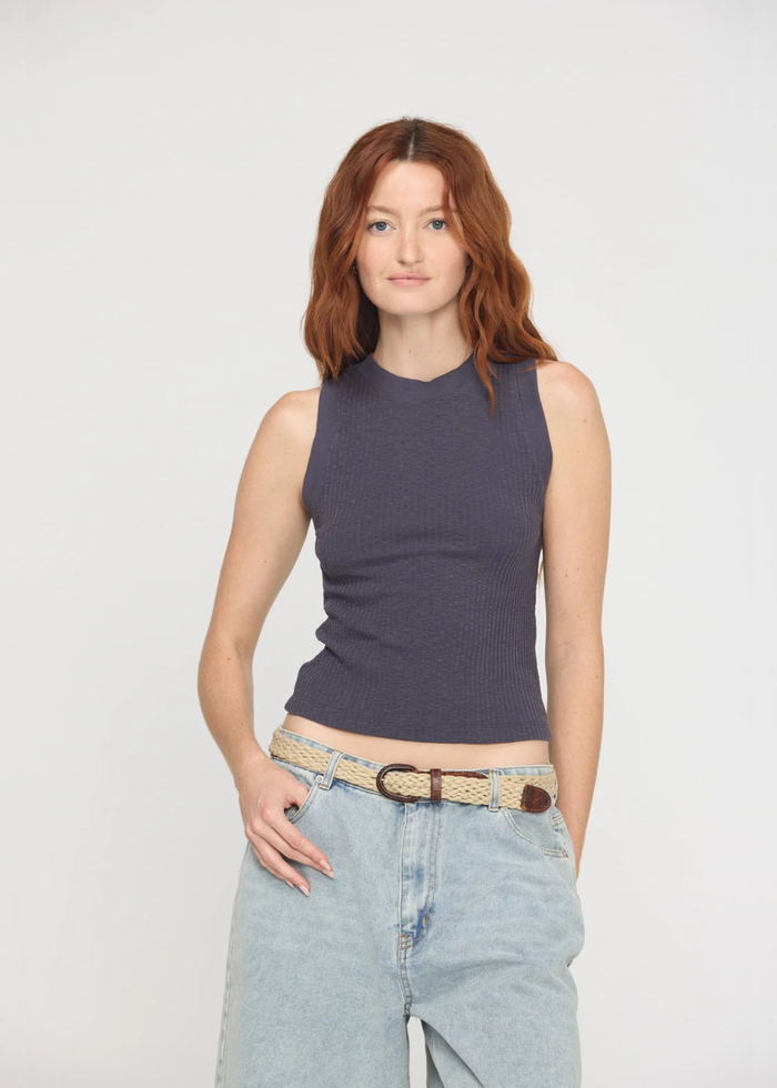 Woman wearing a charcoal grey tank top with a crew neck and a racerback along with denim bottoms and a belt