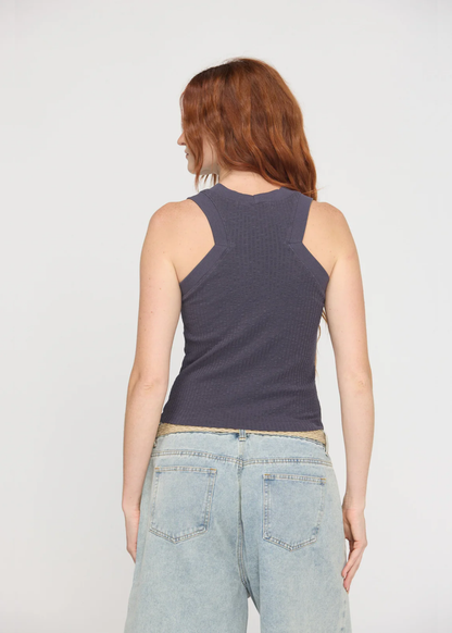 Woman turned around wearing a charcoal grey tank top with a crew neck and a racerback along with denim bottoms and a belt