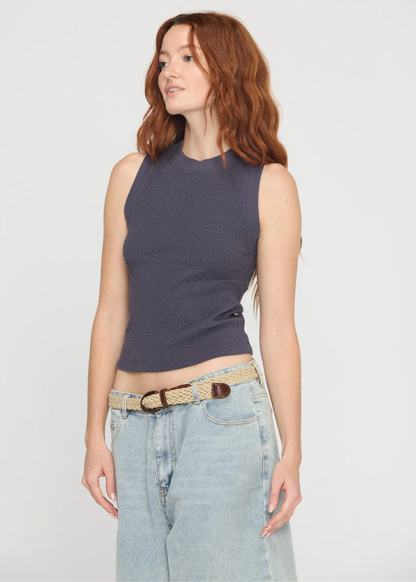Woman wearing a charcoal grey tank top with a crew neck and a racerback along with denim bottoms and a belt