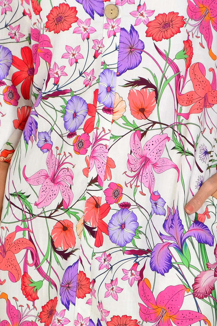 Purple pink floral linen blend tunic by La Mode displayed on a hanger, showcasing its light, airy fabric and vibrant floral pattern.