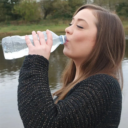 Woman drinking Pyramid Biox Aqua Chlorine Dioxide treated water from a bottle outdoors by a body of water