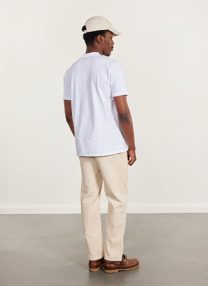 Back view of a model wearing the white Percival Ramen T-shirt with beige corduroy trousers and a cap.