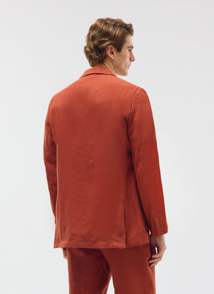 A model, seen from behind, wears the Percival Relaxed Tailored Linen Blazer and matching trousers in rust.