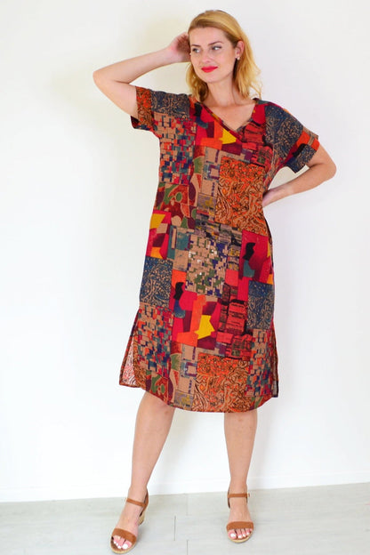 Rust orange Hourglass playful tunic dress with long sleeves and a relaxed fit, displayed on a hanger against a plain background.