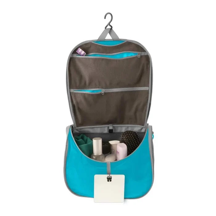 Sea To Summit Hanging Toiletry Bag Large in blue with the lid open to show the hanging  bar on a white background
