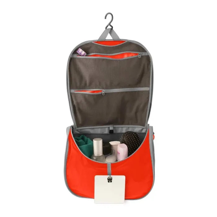 Sea To Summit Hanging Toiletry Bag Large in orange with the lid open to show the hanging  bar on a white background
