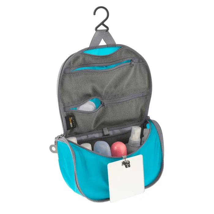 Sea To Summit small Hanging Toiletry Bag in blue with the hanging lid flap unzipped on a white background