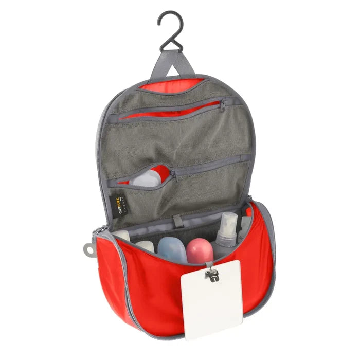 Sea To Summit small Hanging Toiletry Bag in orange with the hanging lid flap unzipped on a white background